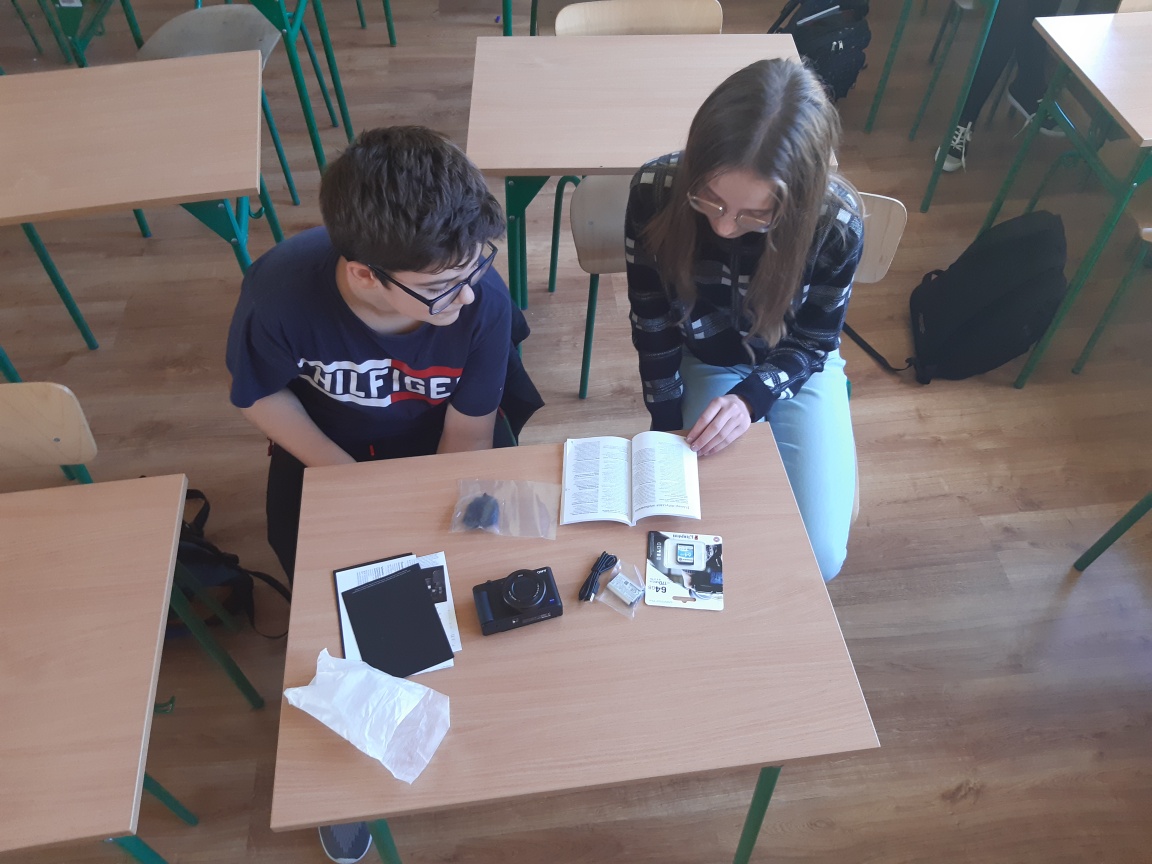dwoje uczniów podczas czytania instrukcji obsługi aparatu cyfrowego i kamery