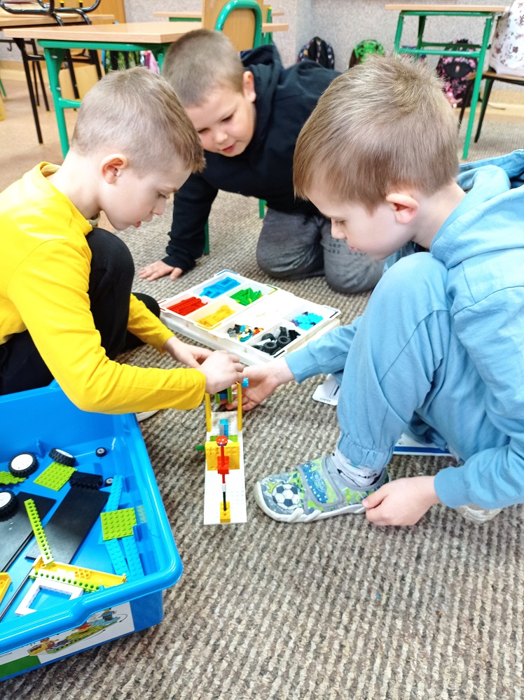 trzech chłopców podczas tworzenia projektu z klocków Lego