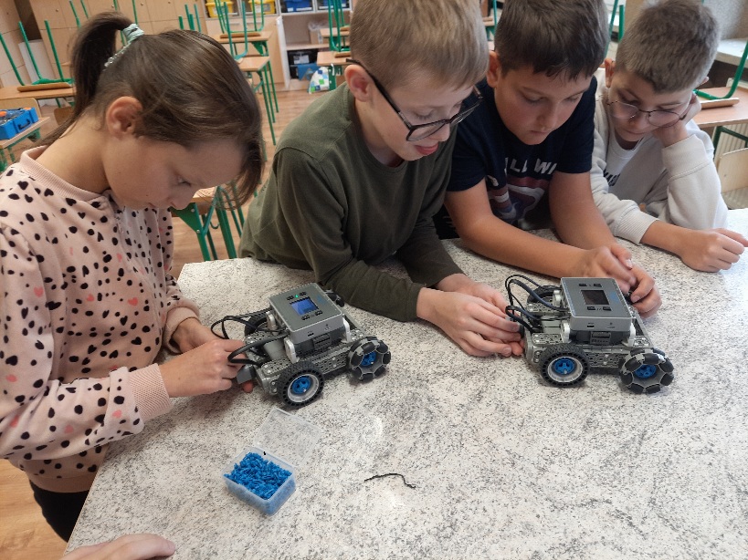 czworo uczniów budujących robota z klocków vex iq