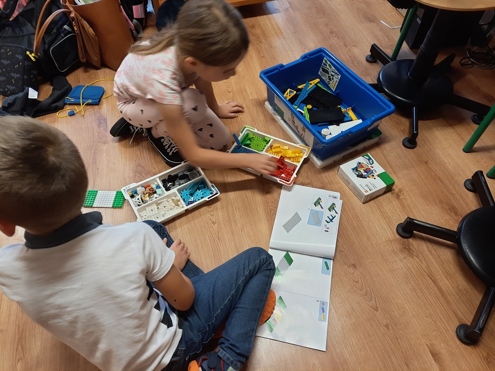 dwoje dzieci tworzących projekt z klocków Lego