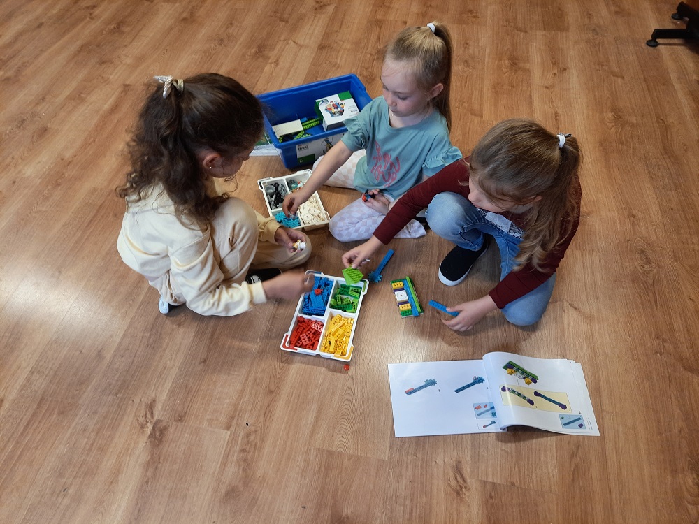 troje dzieci tworzących projekt z klocków Lego