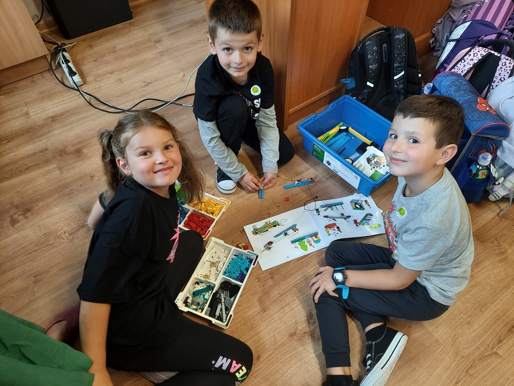 troje dzieci tworzących projekt z klocków Lego