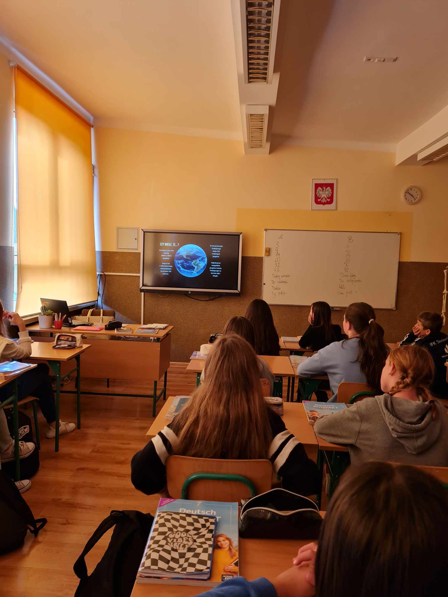 uczniowie siedzący w ławkach podczas oglądania prezentacji