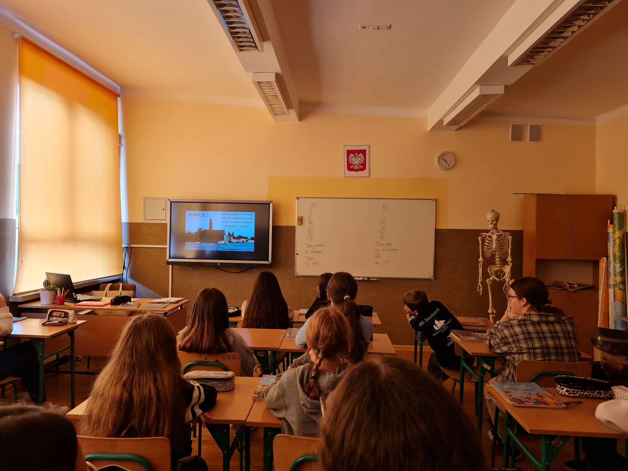 uczniowie siedzący w ławkach podczas oglądania prezentacji