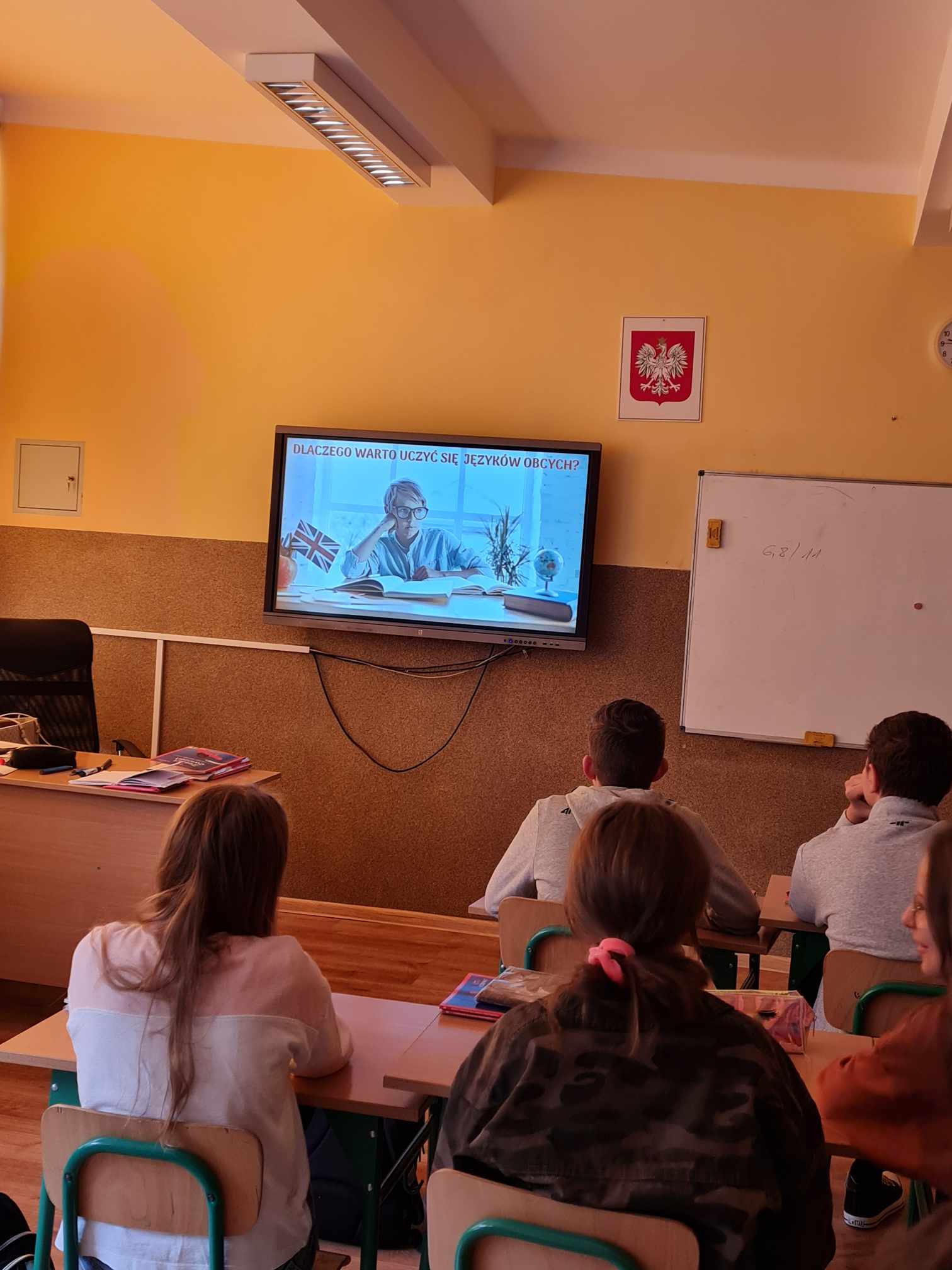 uczniowie siedzący w ławkach podczas oglądania prezentacji