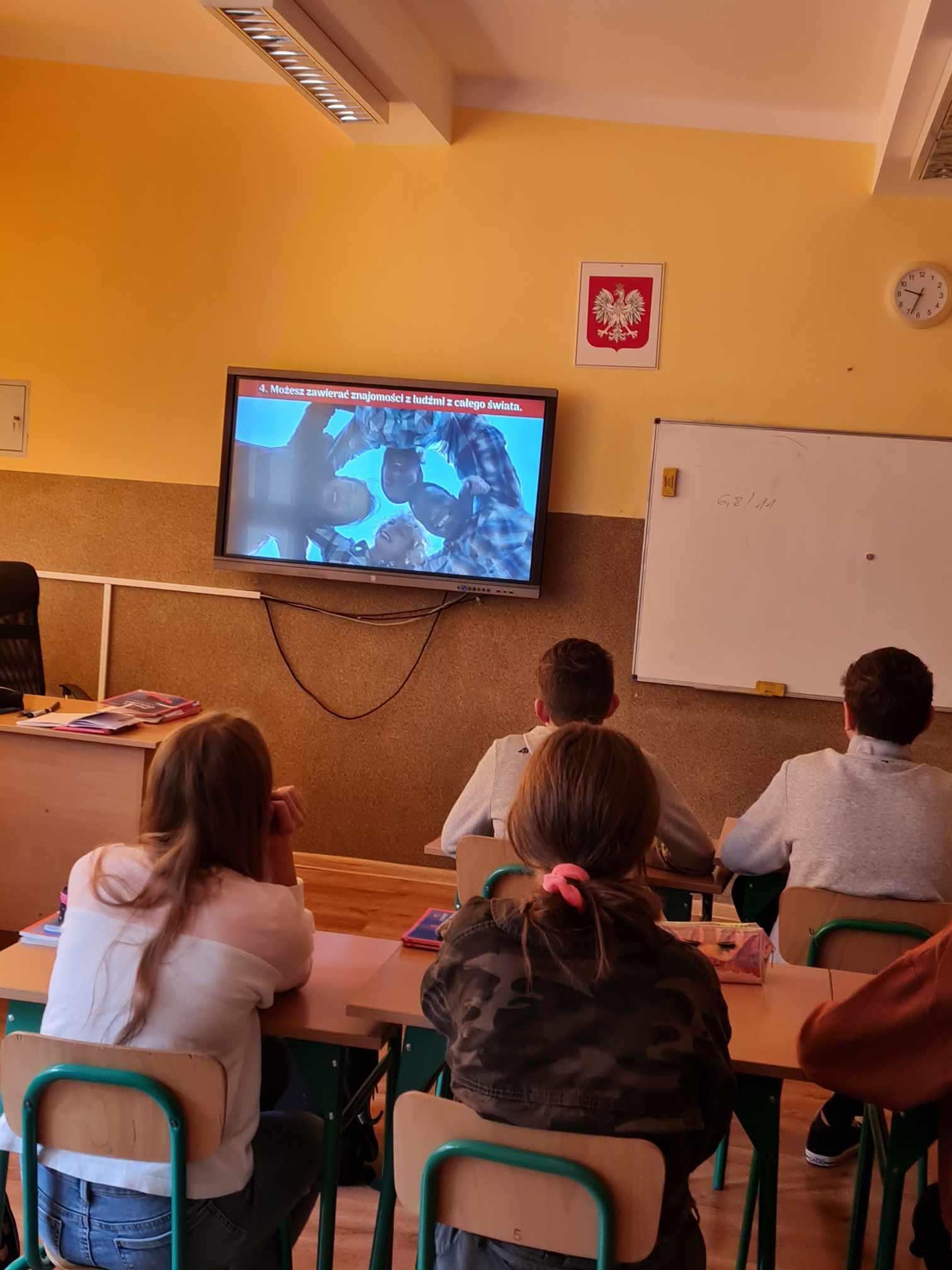 uczniowie siedzący w ławkach podczas oglądania prezentacji