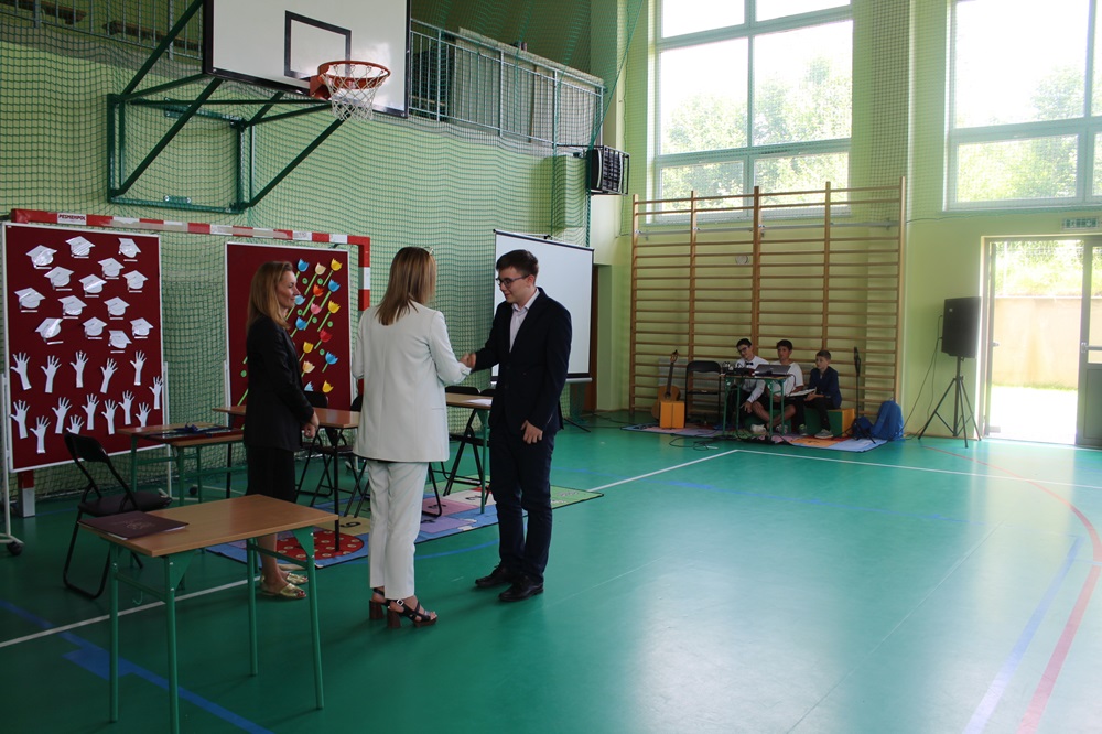 pożegnanie absolwentów szkoły - akademia dyrektor wręczająca nagrodę uczniowi