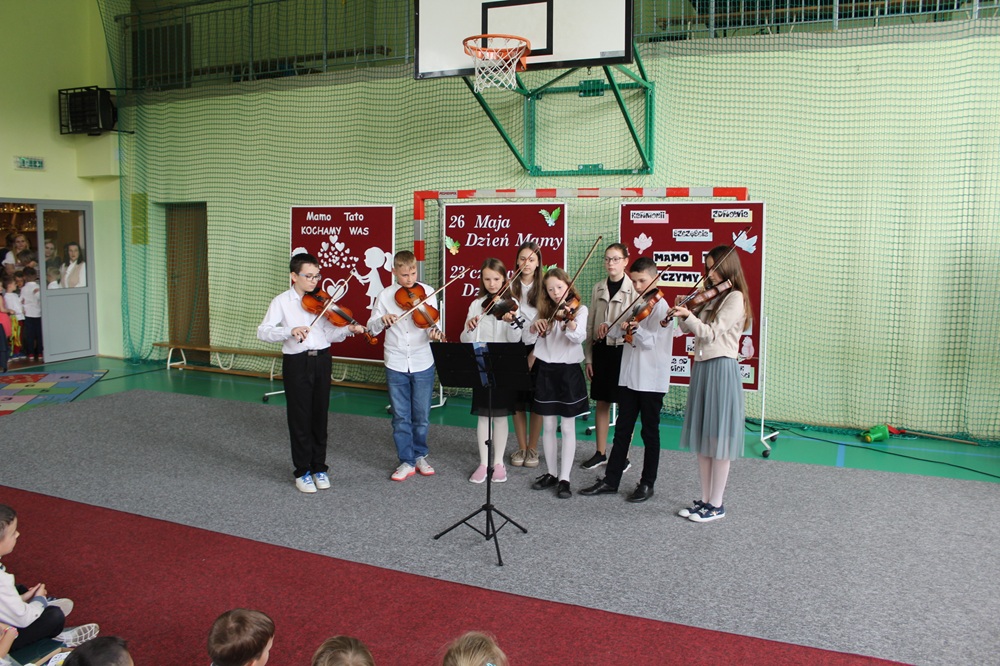 grupa dzieci grających na instrumentach i śpiewających podczas akademii z okazji dnia matki i ojca