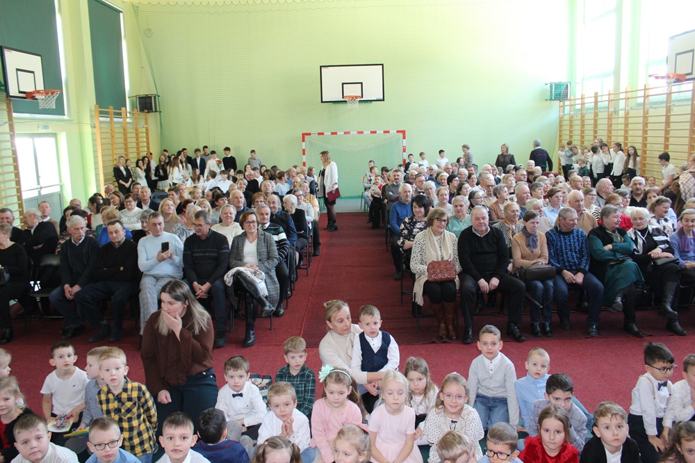 duża grupa dzieci i starszych osób na sali gimnastycznej podczas akademii z okazji dnia babci i dziadka