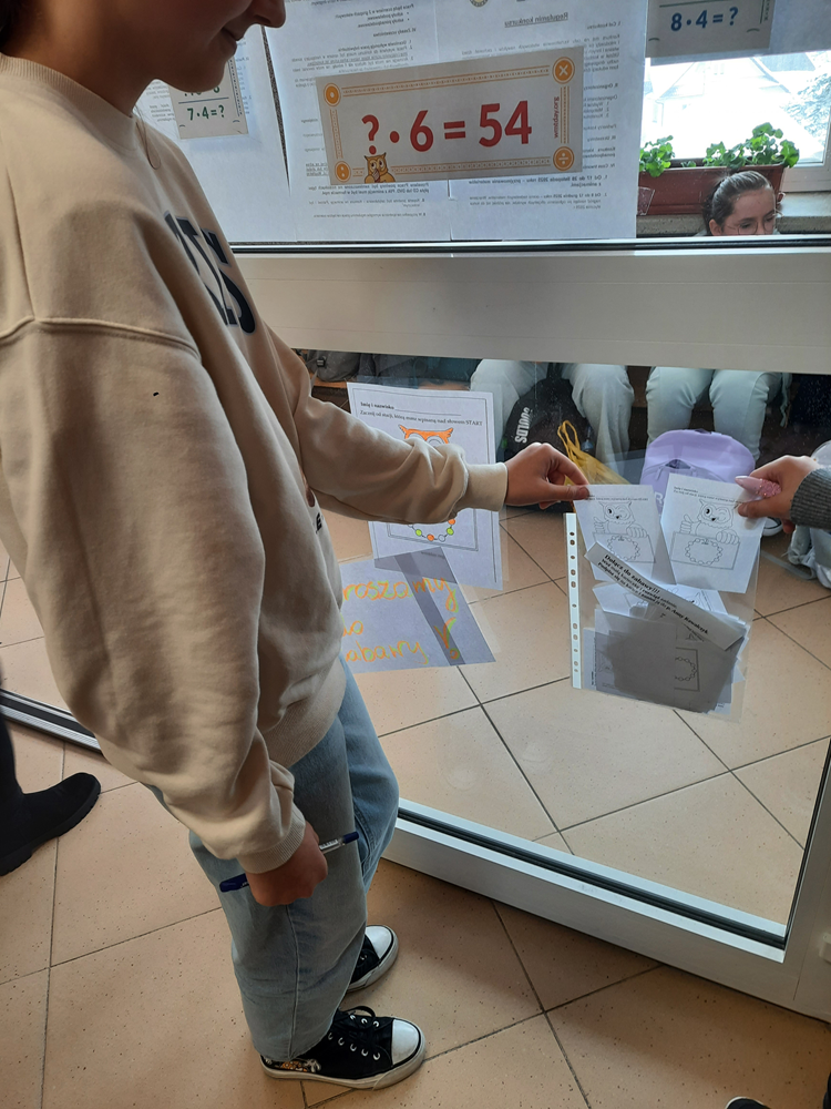 uczennica rozwiązująca zadanie matematyczne rozwieszone na szkolnych korytarzach z okzji światowego dnia tabliczki mnożenia