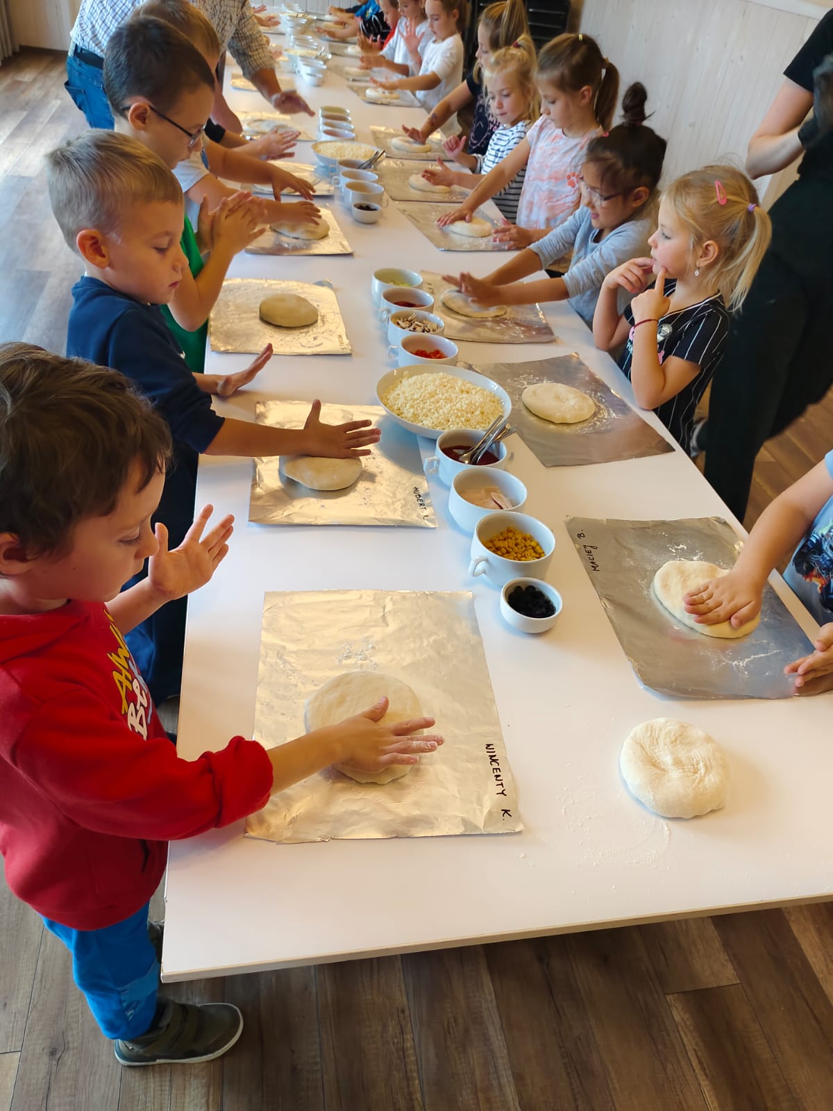 kilkanaścioro dzieci podczas robienia pizzy