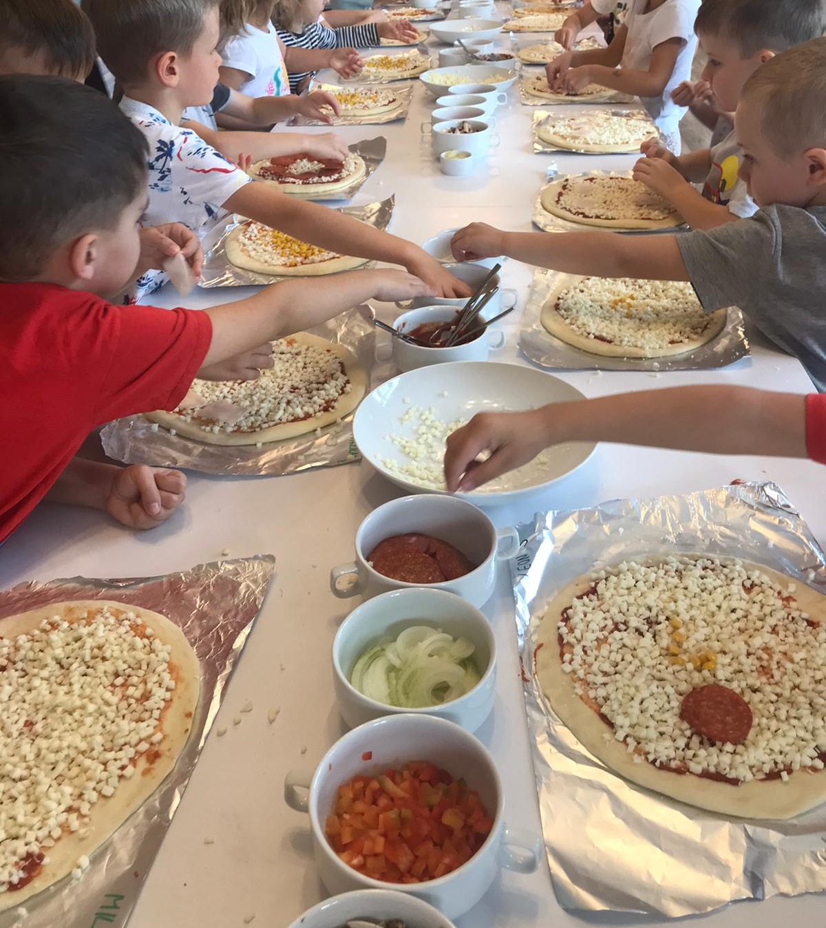 kilkoro dzieci podczas robienia pizzy